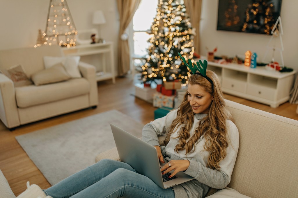Junge Frau arbeitet an Weihnachten am Laptop.