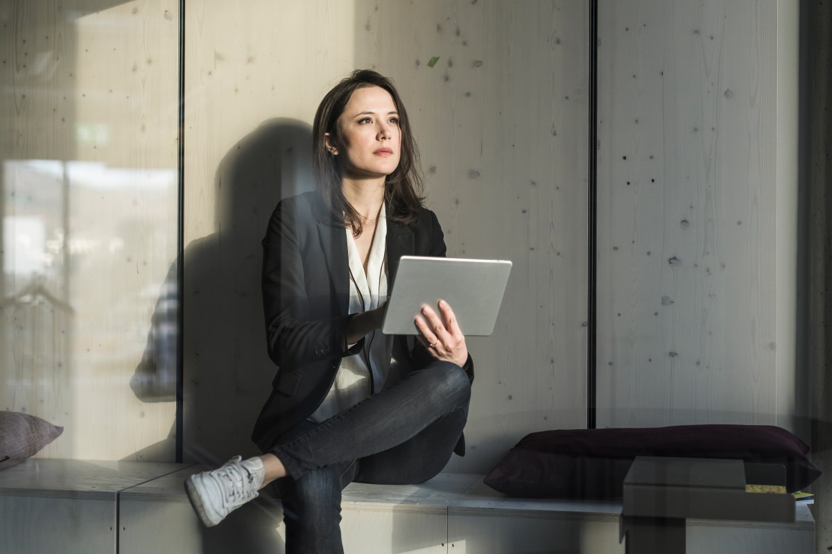 Geschäftsfrau mit Tablet sitzt im Loungebereich im Büro.