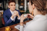 Kaffeetassen-Test: Geschäftsmann, der mit einer Frau ein Gespräch führt. Sie trinkt einen Kaffee.