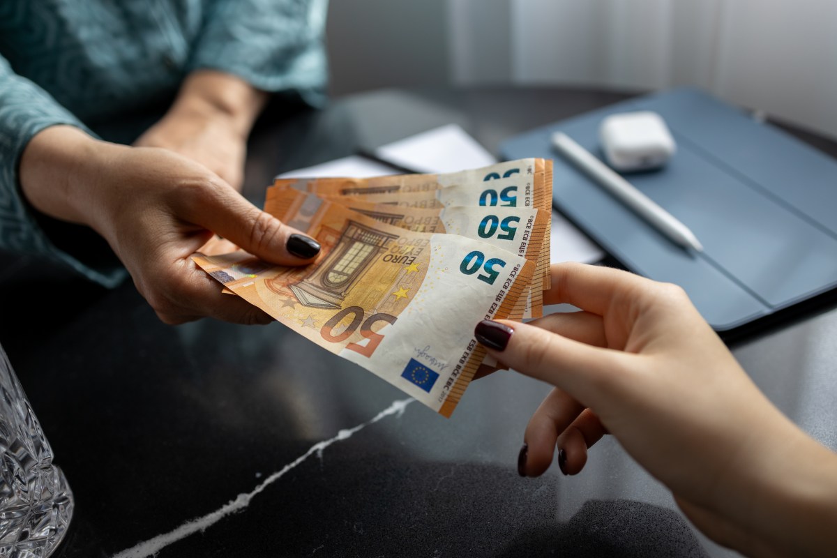 Frau überreicht Frau Euro-Banknoten.