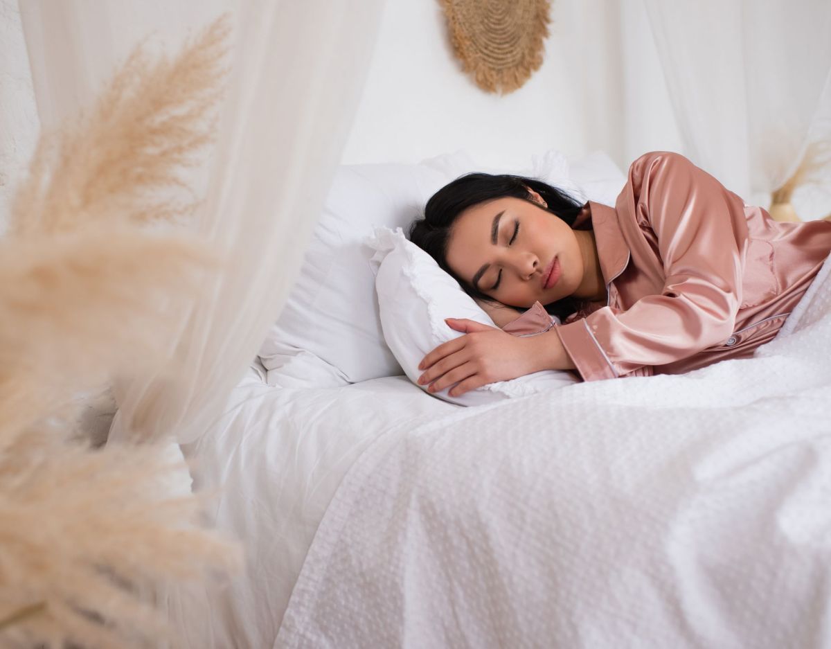 Frau schläft im Bett auf einem Kopfkissen. Beauty Influencer Dejan verrät: Schonende Schlaffrisuren für deine Haare