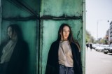 Junge Frau steht in der Nähe einer grünen Wand und schaut weg.