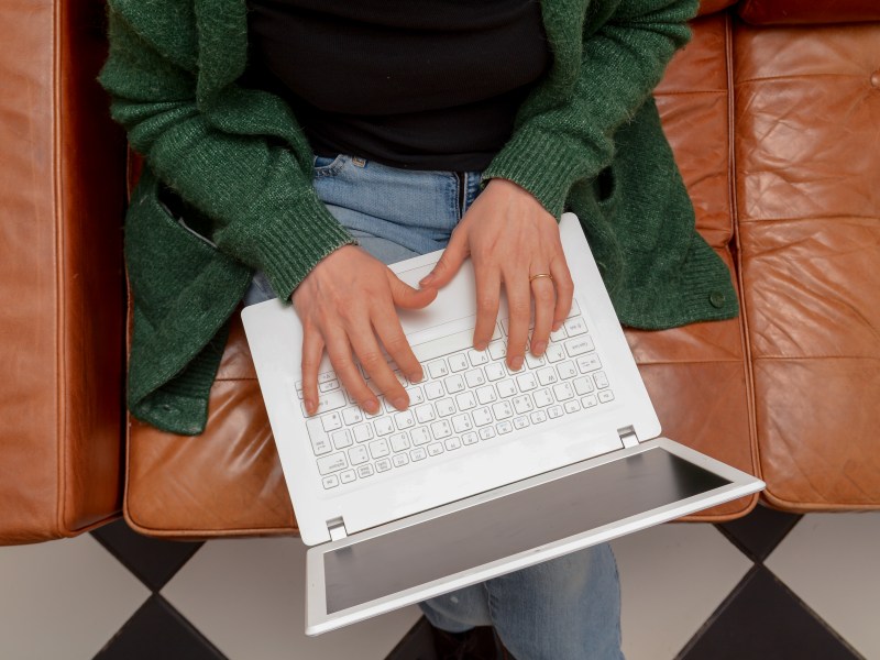 Frau zu Hause mit Laptop-Computer auf der Couch.