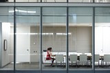 Eine Frau sitzt alleine in einem Meeting-Raum.