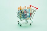 Stillleben mit Einkaufswagen und Euro-Scheinen auf türkisfarbenem Hintergrund