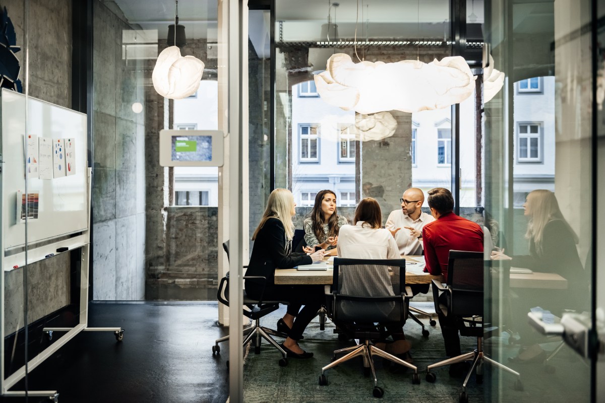 Eine Gruppe von Personen sitzt während eines Meetings in einem hellen, modernen Büro an einem Tisch.