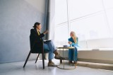 Zwei Frauen sitzen in Sesseln und unterhalten sich.