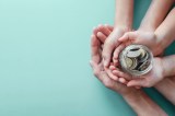 Kinder- und Elternhände halten Geldkrug.