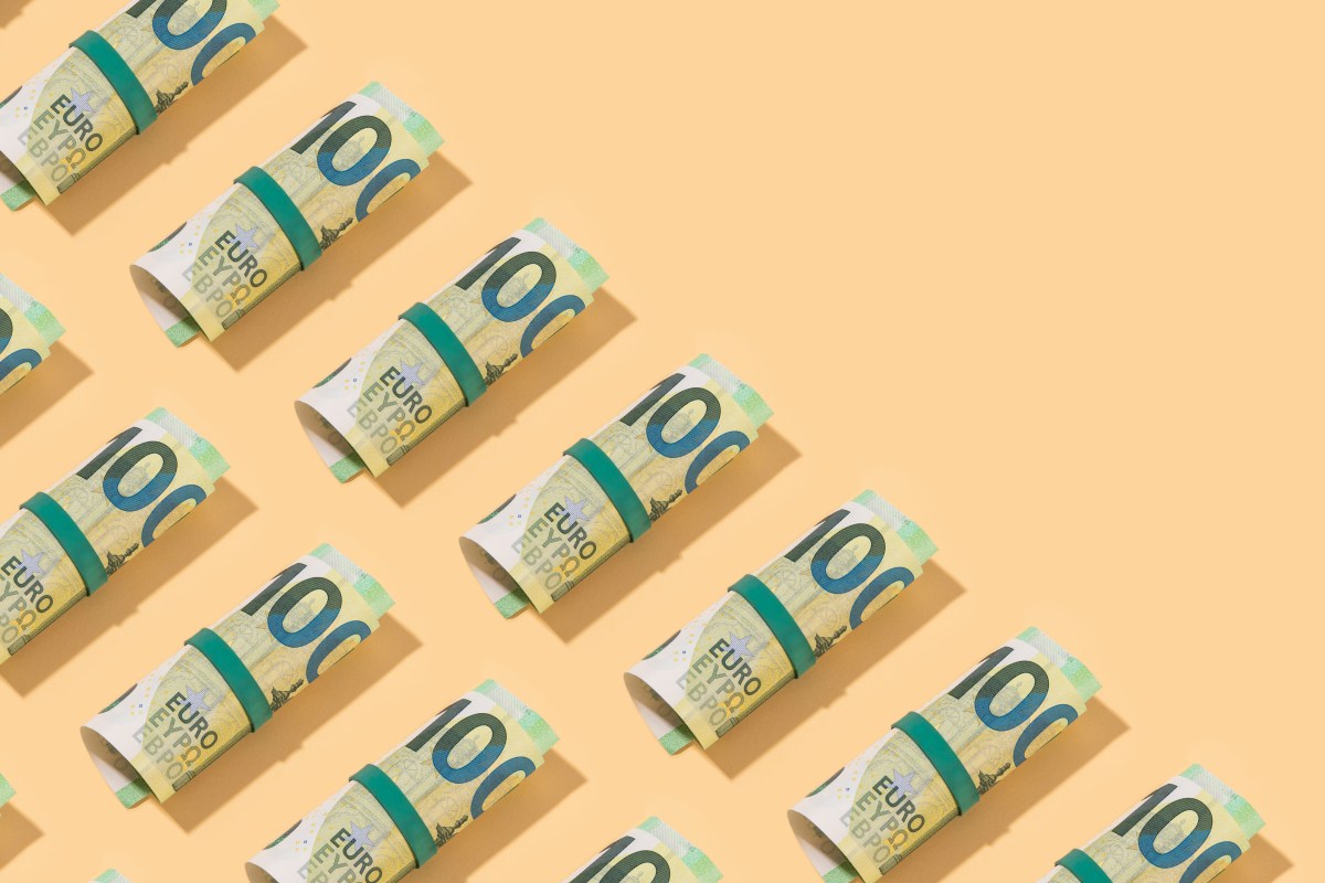 Rolle von Hundert-Euro-Scheinen auf orangenen Hintergrund.