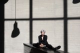 Frau im eleganten schwarzen Kleid mit Wand mit Schatten im Hintergrund.