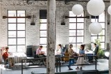 Mehrere Personen arbeiten in einem Großraumbüro.