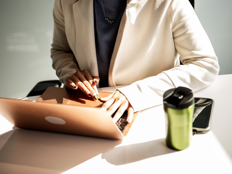 Eine Frau im beigen Blazer arbeitet am Laptop.