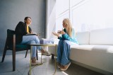 Zwei Frauen sitzen in Sesseln und unterhalten sich.
