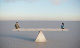 Mann und Frau sitzen auf einer Betonwippe und symbolisieren damit die Gleichberechtigung der Geschlechter.