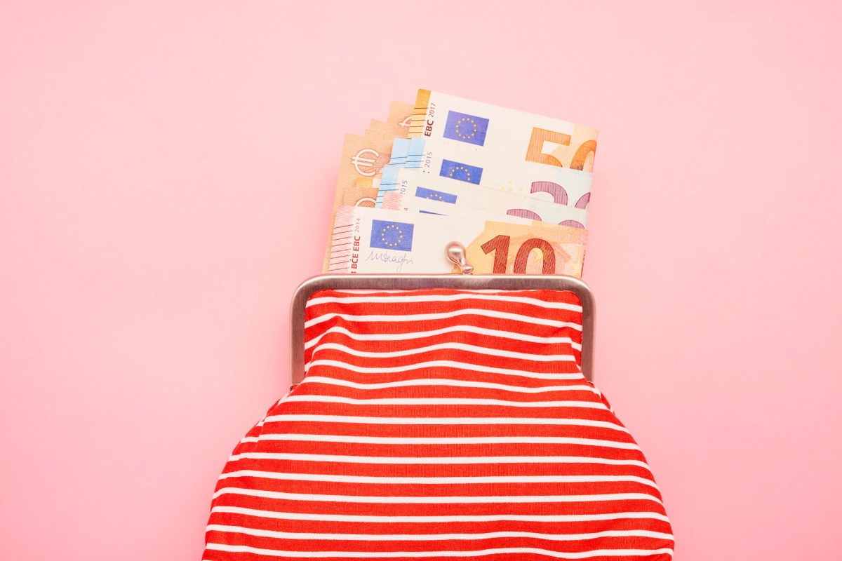 Aufnahme einer Brieftasche und Euro-Banknoten auf rosa Hintergrund.
