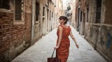 Eine Frau mit Sonnenbrille geht durch die Gassen einer italienischen Stadt.
