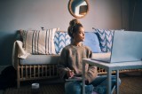 Junge Frau schreibt auf ihrem Sofa ein Journal.