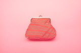 Ansicht einer rot-weiß gestreiften Brieftasche auf rosafarbenem Hintergrund.