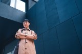 Frau posiert selbstbewusst im Freien vor einem Gebäude.