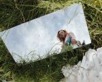 Ein Spiegel liegt im Gras und im Spiegelbild sieht man eine Frau, die hineinschaut.