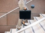 Eine Frau mit einer schwarzen Aktentasche läuft eine Treppe hoch.