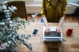 Eine Frau arbeitet am Laptop. Daneben liegt ihr Handy.