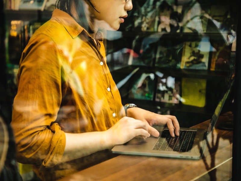 Asiatische Frau arbeitet remote an einem Laptop.