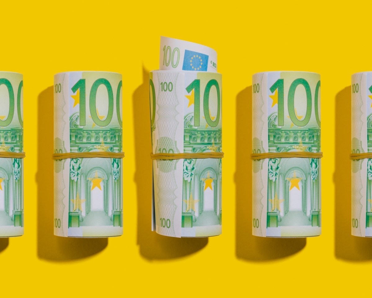 100-Euro-Rollen liegen flach auf gelbem Hintergrund.