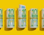 100-Euro-Rollen liegen flach auf gelbem Hintergrund.