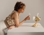 Frau mit einer Feder in der Hand vor einem Ventilator.
