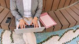Nahaufnahme der Hände einer Frau, die elegant auf einer Laptoptastatur tippt.
