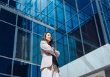 Junge Asiaten steht vor einem Bürogebäude und hat die Arme verschränkt.