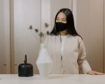 Frau mit Maske in einem beigefarbenen Wohnzimmer