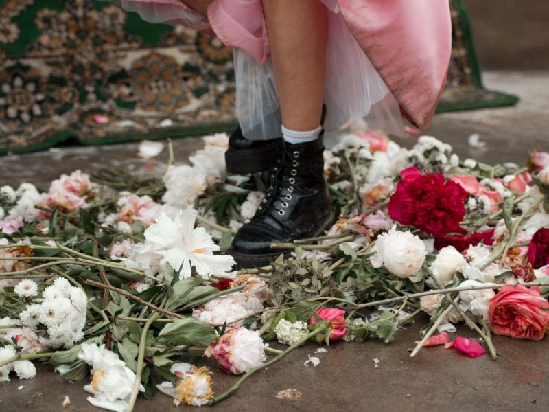 Frau mit Stiefeln steht auf Blumen