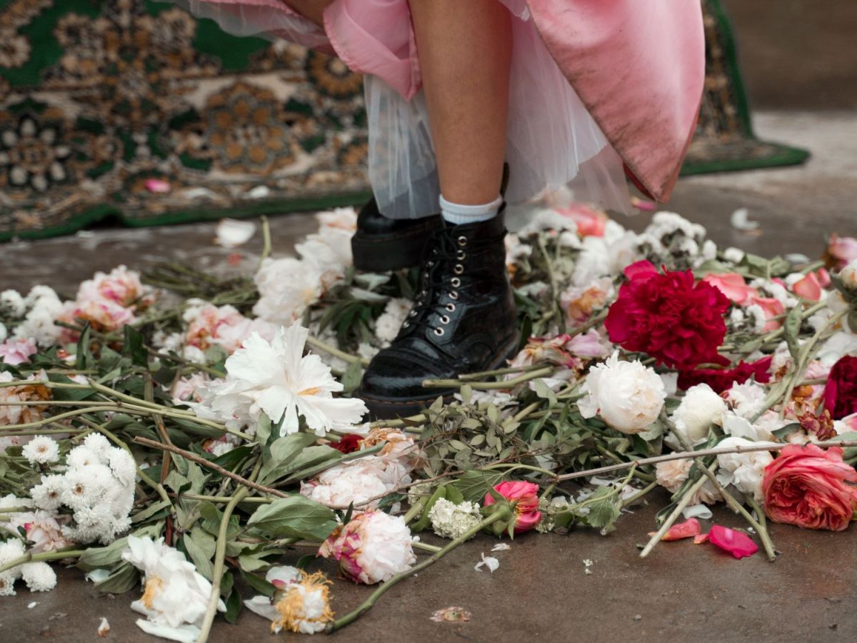 Frau mit Stiefeln steht auf Blumen