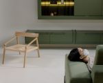 Frau liegt mit einer Maske vor dem Mund auf einem grünen Sofa
