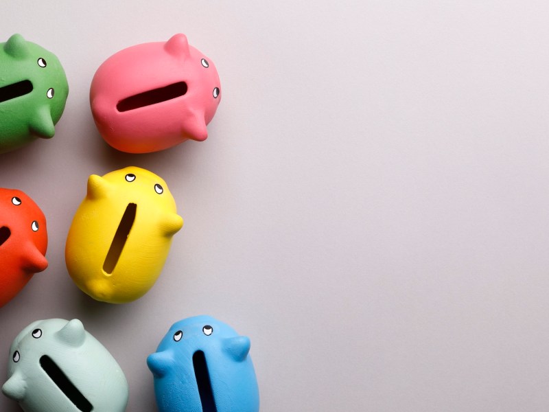 Bunte Sparschweine auf beigen Hintergrund.