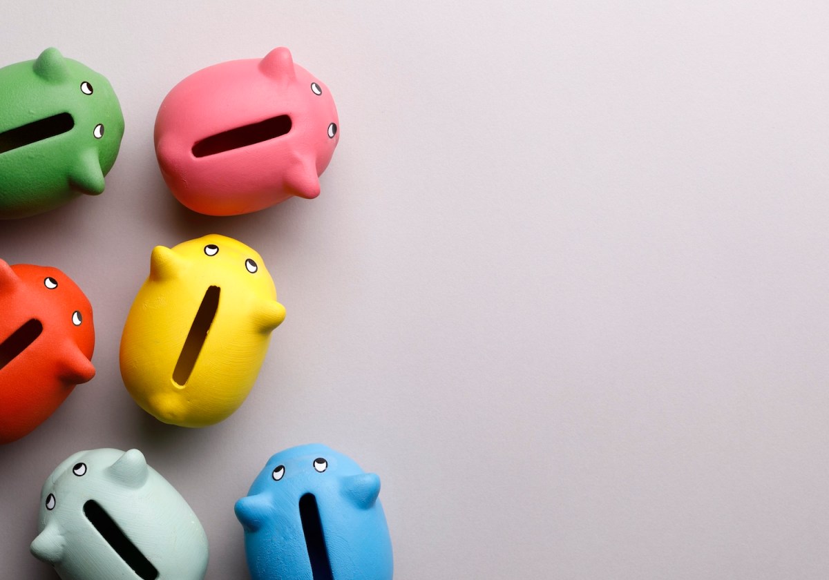 Bunte Sparschweine auf beigen Hintergrund.