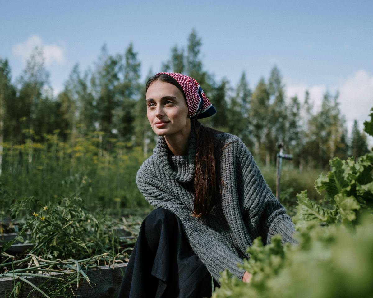 Frau kniet auf einem Feld und erntet