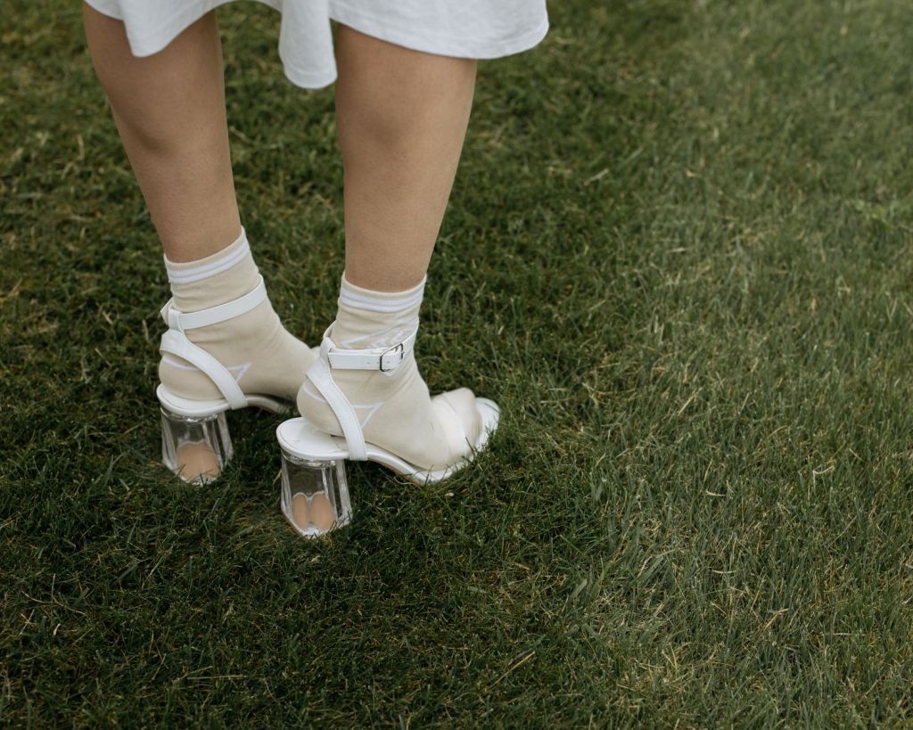 Frau mit Absatzschuhen auf grünem Rasen