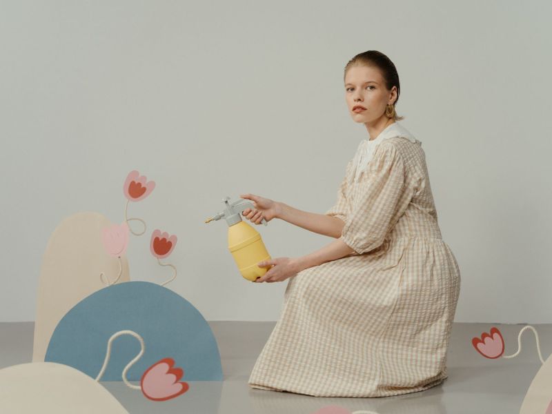 Frau gießt Plastik-Blumen