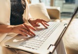 Nahaufnahme der Hände einer Frau, die auf der Laptoptastatur tippt.