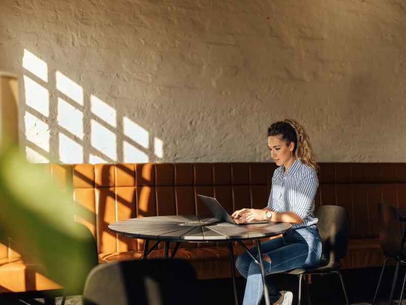 Blondes Mädchen arbeitet allein im Coworking-Space am Laptop.