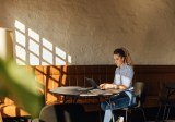 Blondes Mädchen arbeitet allein im Coworking-Space am Laptop.