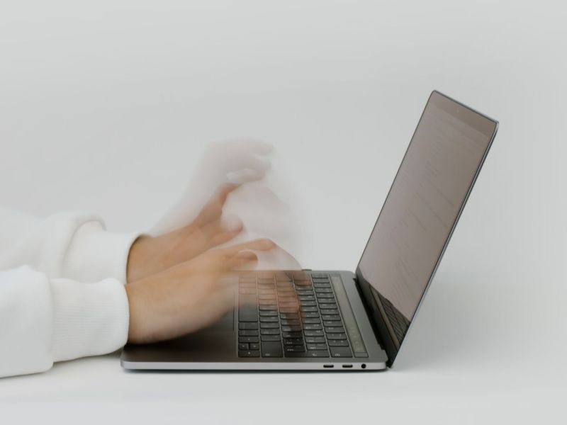 Verschwommene Hände tippen auf einem Laptop.