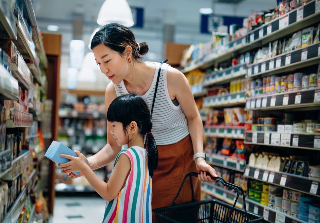 Eine Mutter und ihre Tochter schauen sich im Supermarkt ein Produkt an.