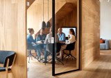 Geschäftsleute diskutieren in einem Meeting, gesehen durch die Glastür im Büro.