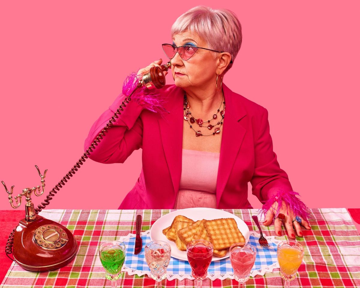 Oma sitzt an einem gedeckten Tisch und telefoniert.