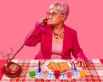 Oma sitzt an einem gedeckten Tisch und telefoniert.