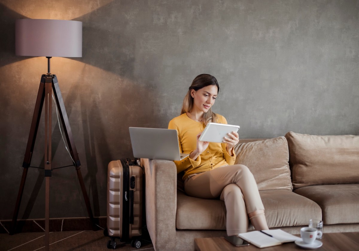 Geschäftsfrau nutzt digitales Tablet, während sie auf Geschäftsreise vom Hotelzimmer aus arbeitet.